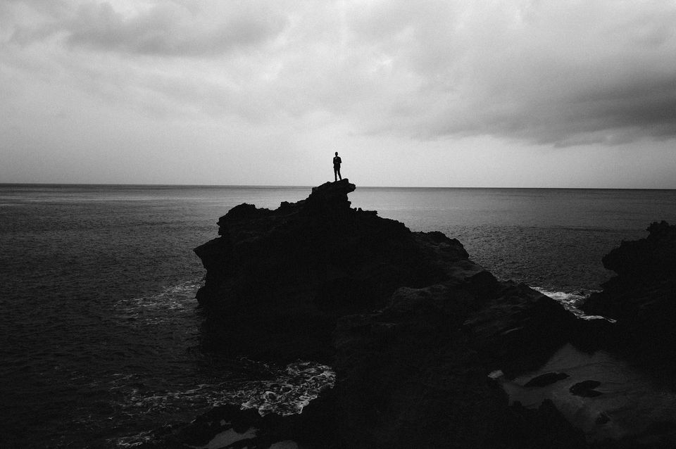 Solitary figure standing on a cliff overlooking the ocean