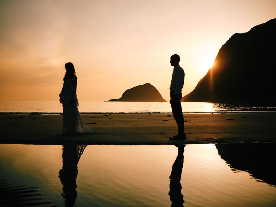 Couple silhouetted on beach at golden hour