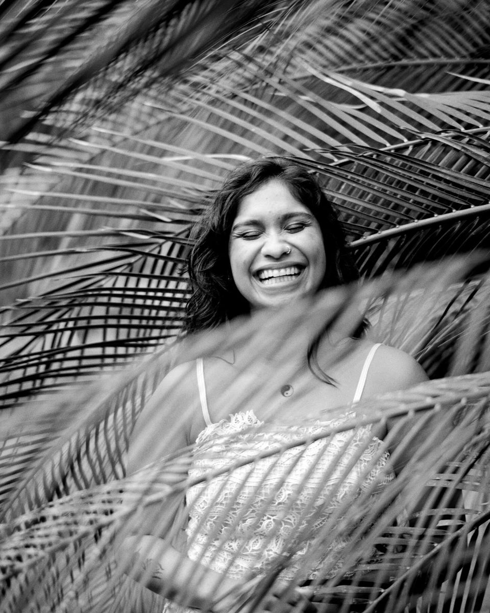 Woman laughing through palm fronds